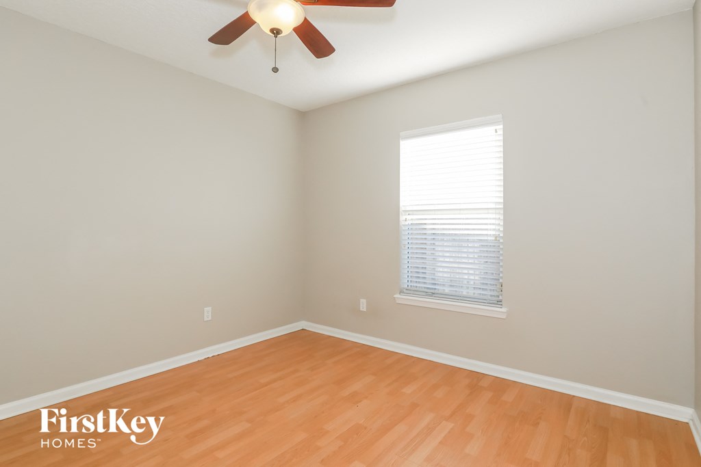 a bedroom with wood floors and a ceiling fan