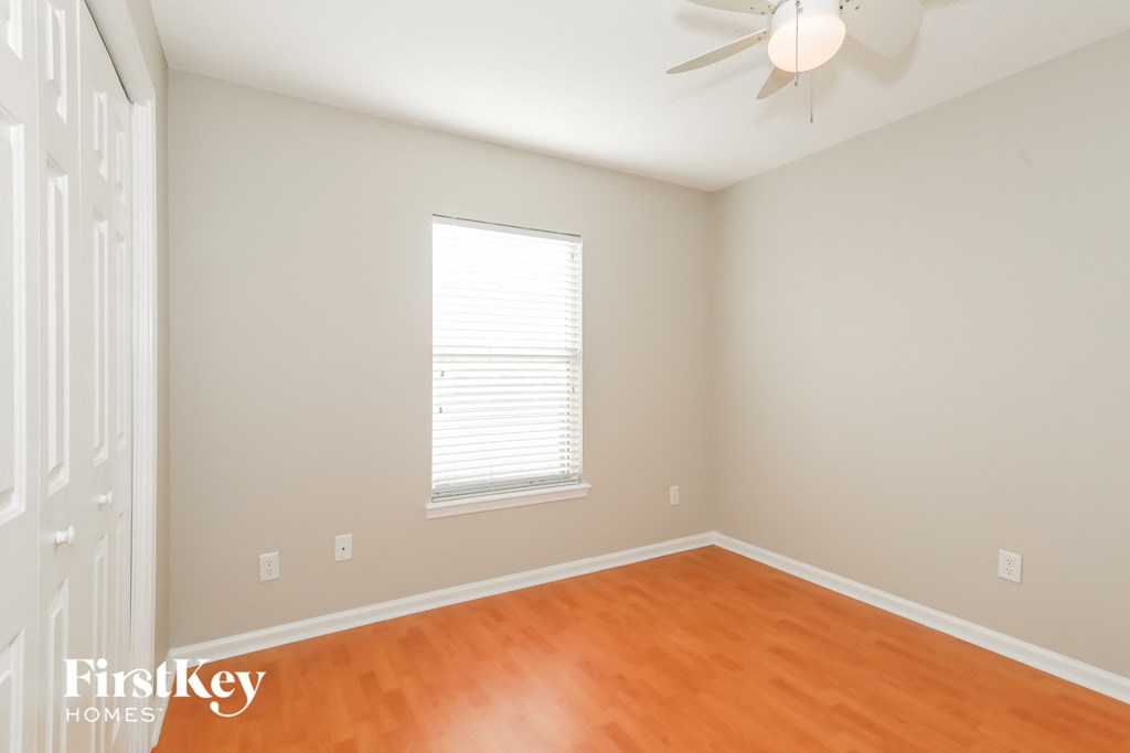 a bedroom with wood floors and a ceiling fan