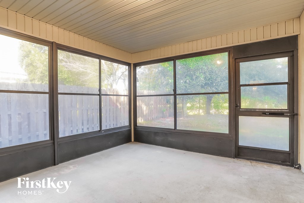 the screened in porch of a home with large windows