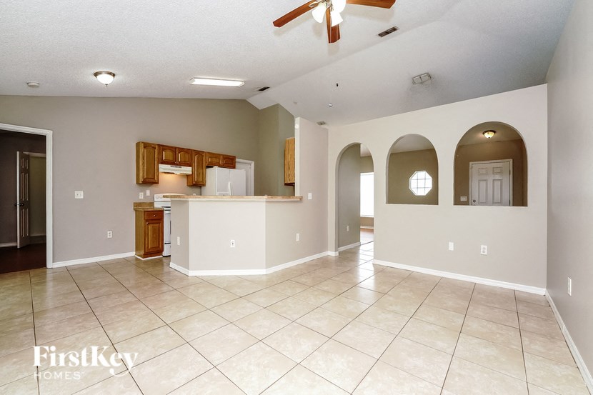 an empty living room and kitchen with a ceiling fan