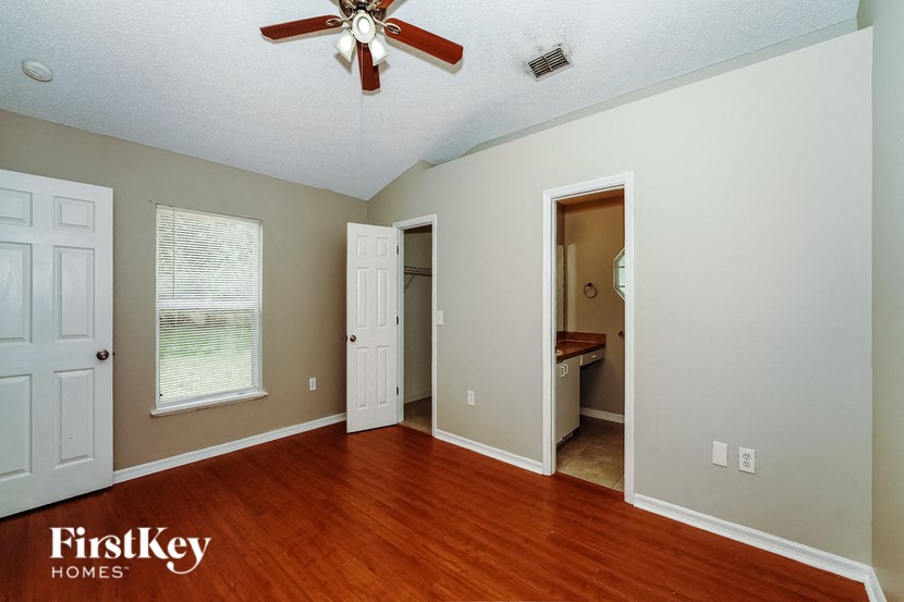 the master bedroom with hardwood flooring and a ceiling fan