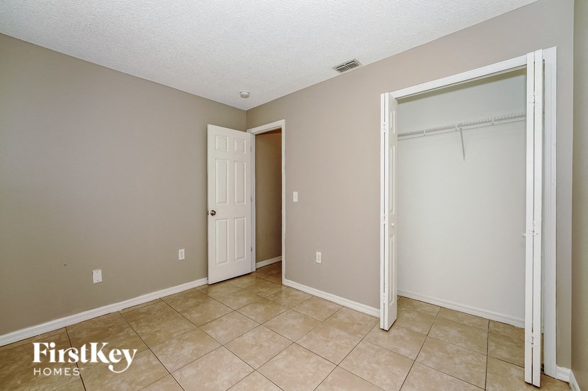 a bedroom with a door to a closet and a tiled floor