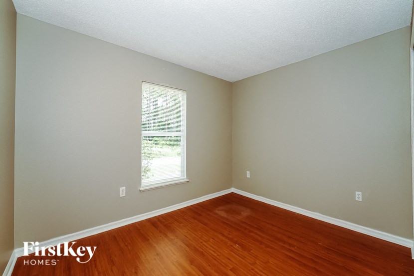 the second bedroom with hardwood flooring and a window