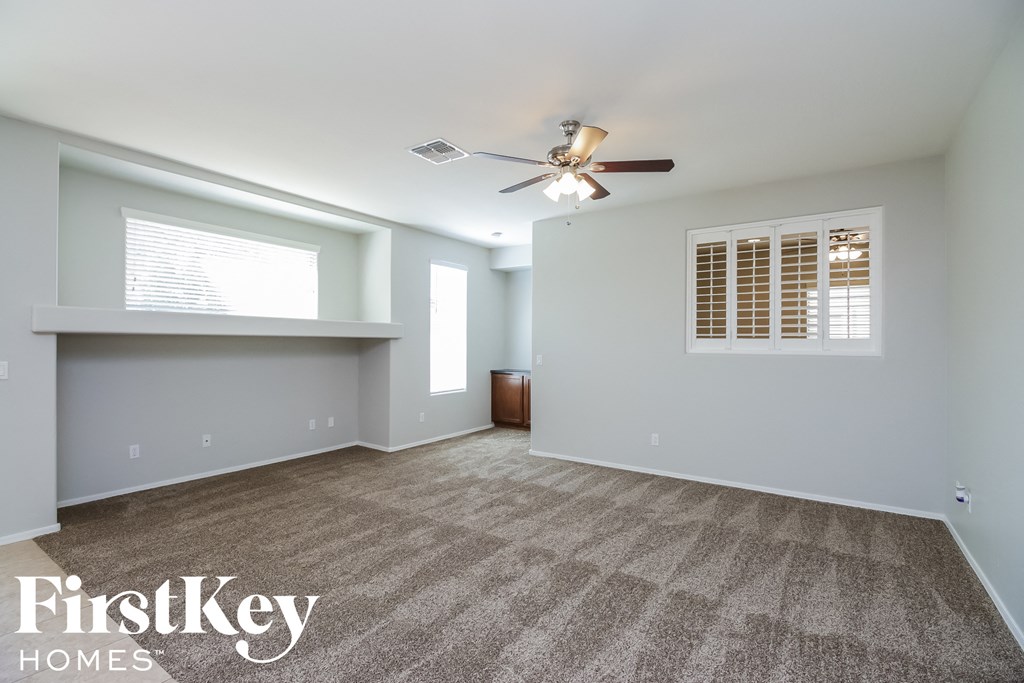 A spacious room with a carpeted floor and a ceiling fan.