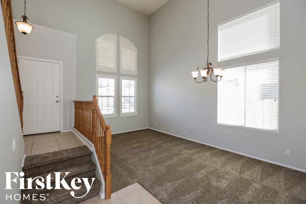 A room with a carpeted floor and a staircase leading to the next room.