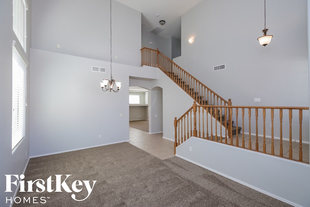 A spacious room with a staircase and a chandelier.