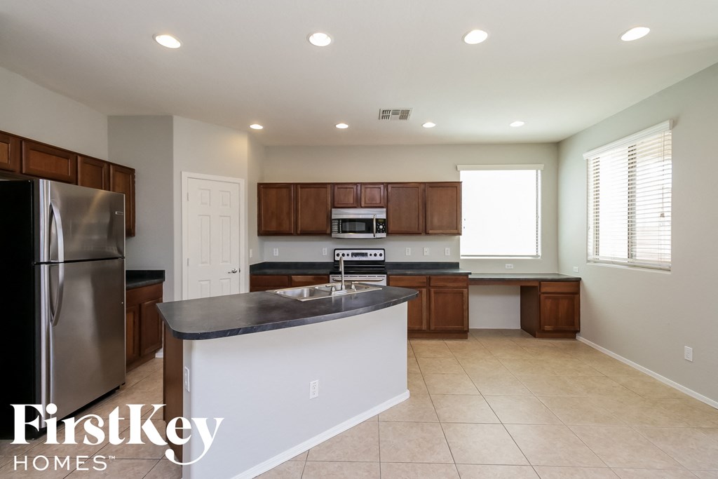 A kitchen with a refrigerator, sink, and cabinets.