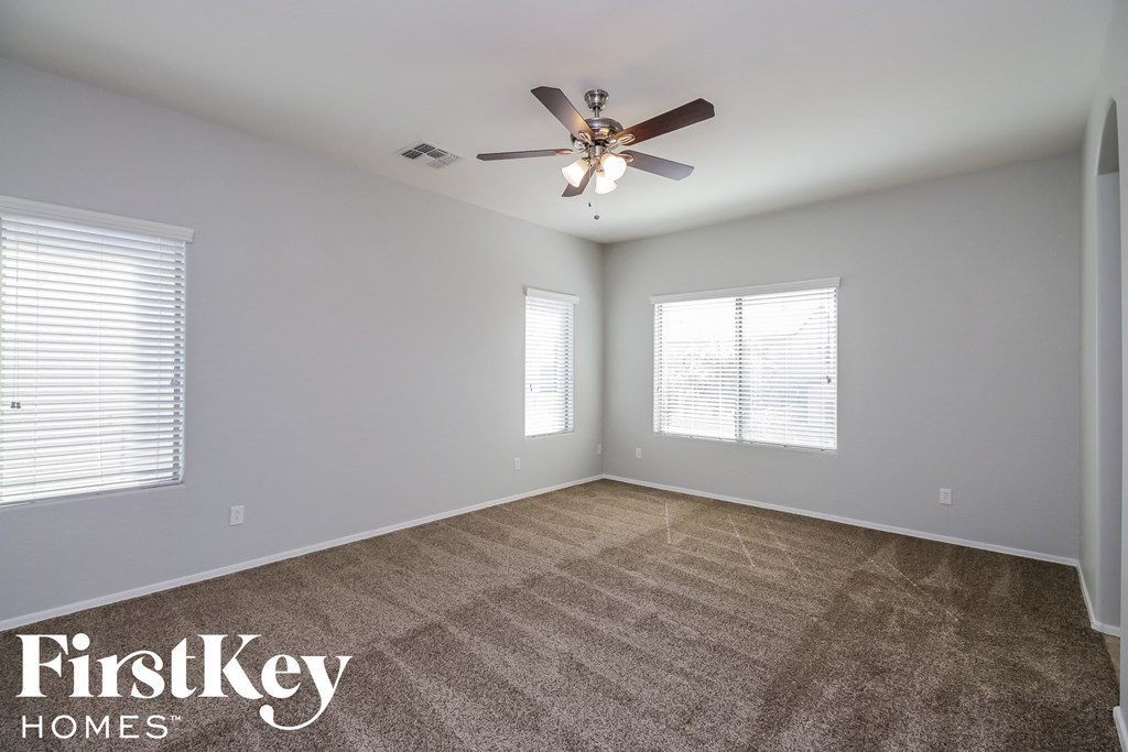 A spacious room with a ceiling fan and carpeted floor.