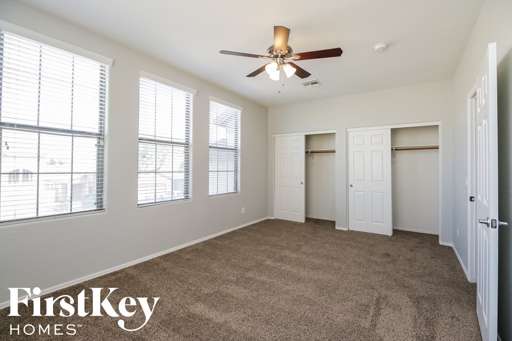 A spacious room with a carpeted floor, a ceiling fan, and a large window.