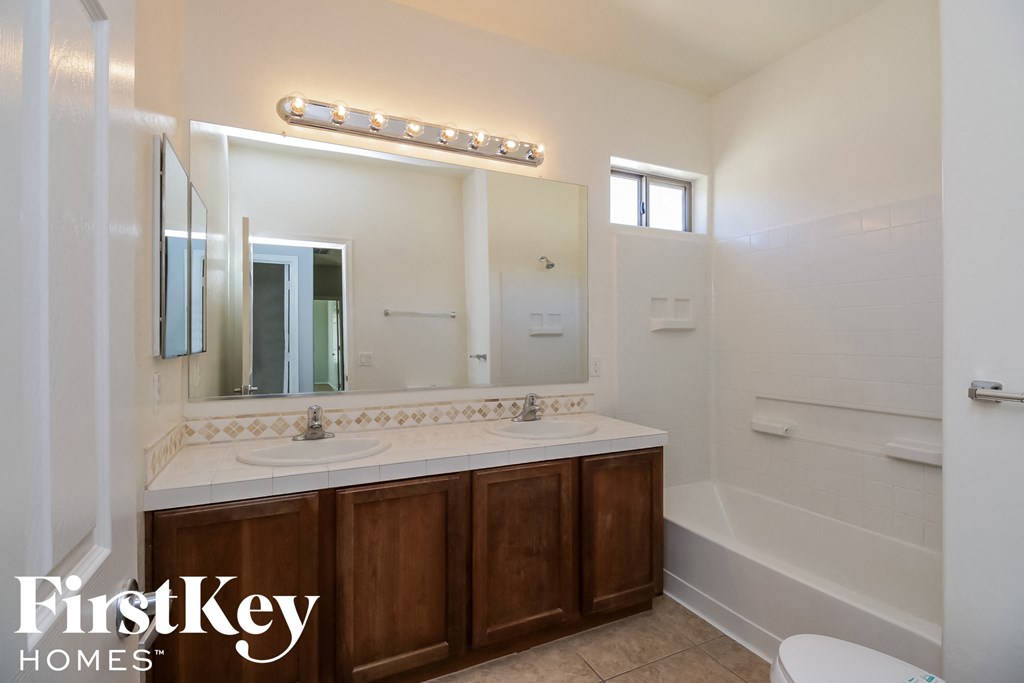 A bathroom with a white sink and a mirror with lights above it.
