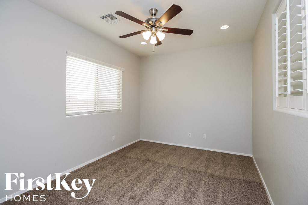 A room with a ceiling fan and a window with blinds.