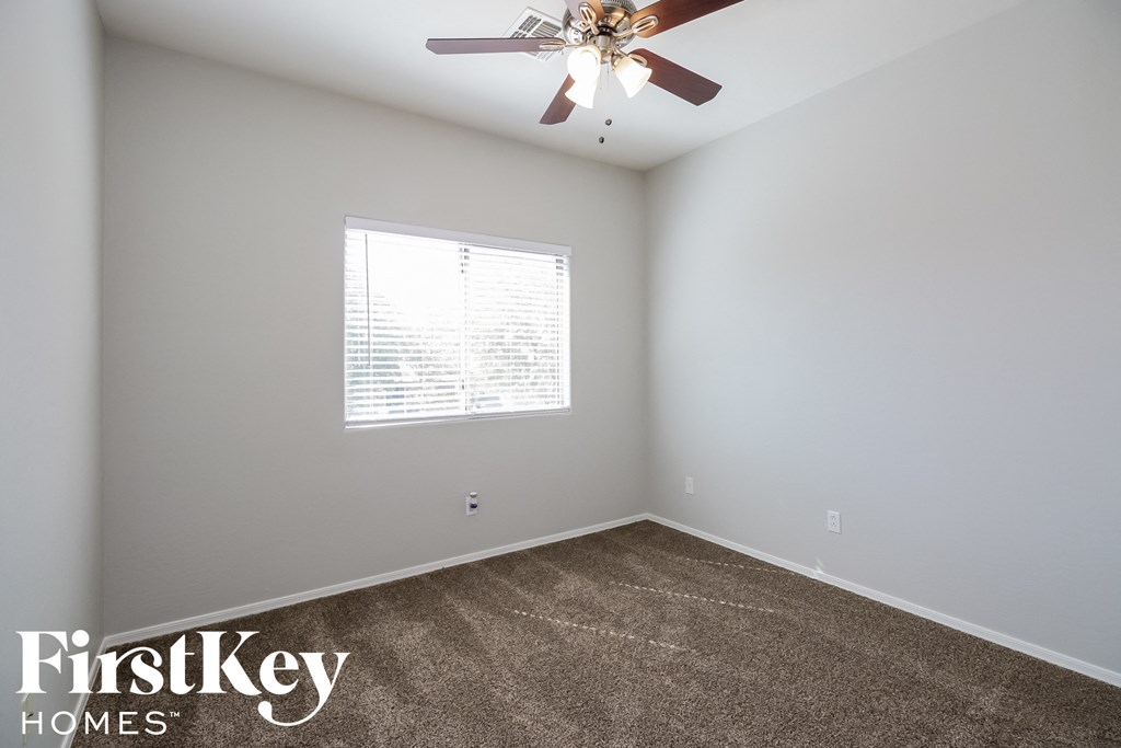 A room with a ceiling fan and a window with blinds.