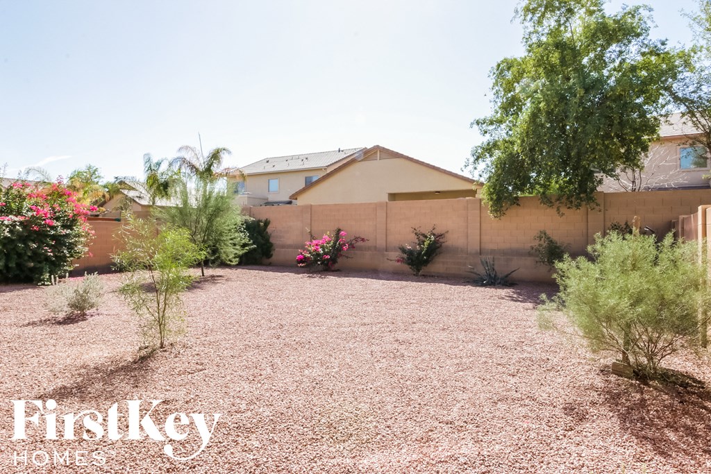 A house with a brown roof and a gravel yard with a tree and plants.