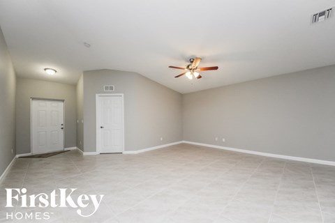 the spacious living room with tile flooring and a ceiling fan