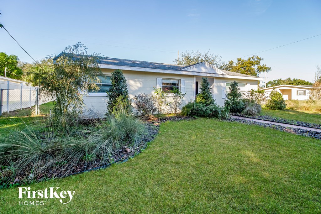 a small white house with a yard and grass