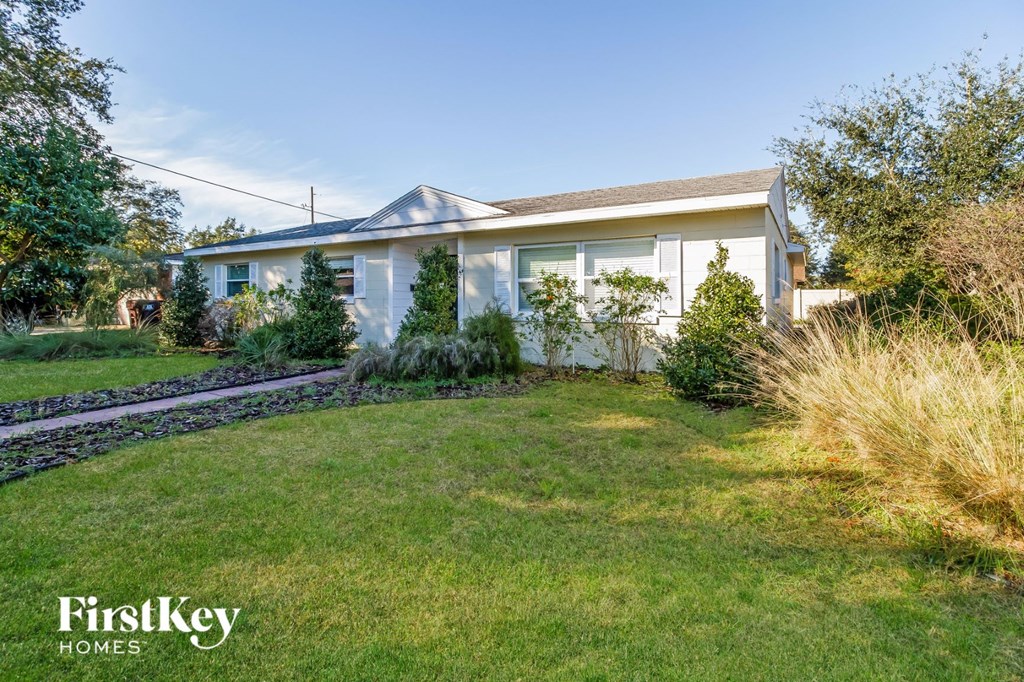 a small white house with a yard and grass