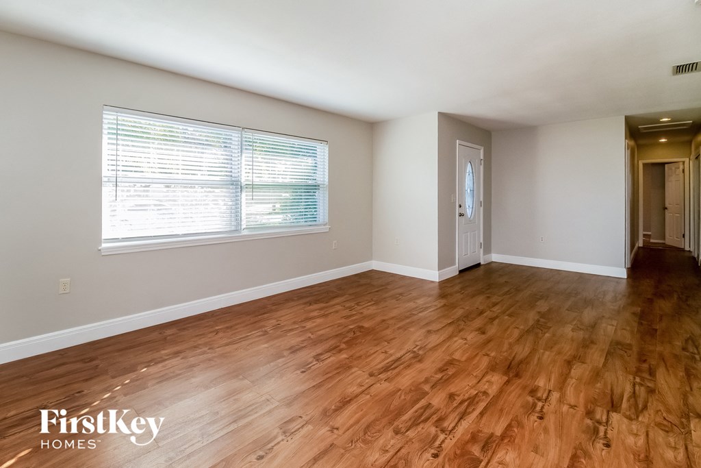 the living room and dining room with wood flooring and a large window