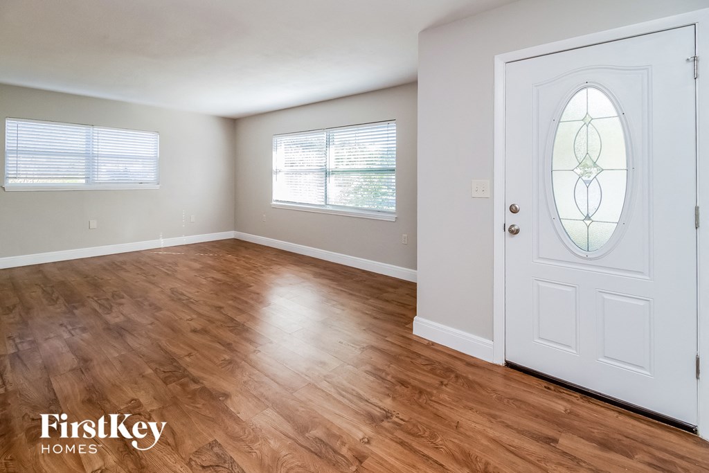 an empty living room with a white door and wood floors