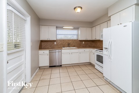 a kitchen with white cabinets and white appliances and tiled floors