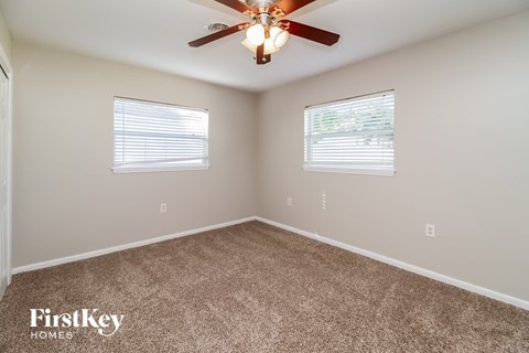 the spacious bedroom with carpet and a ceiling fan