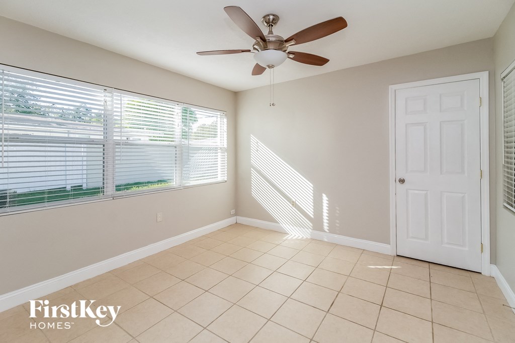 an empty living room with a ceiling fan and a window