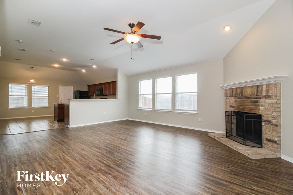an empty living room with a fireplace and a ceiling fan