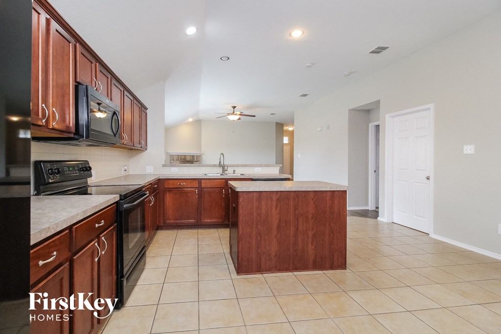 a kitchen with wooden cabinets and a black stove and a sink