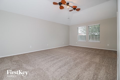 the living room of a home with carpet and a ceiling fan