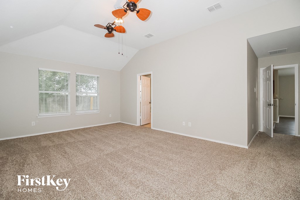 a spacious living room with carpet and a ceiling fan