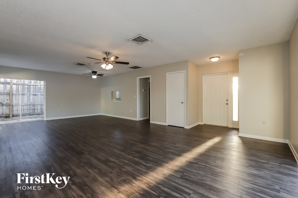 A spacious room with wooden floors and a ceiling fan.