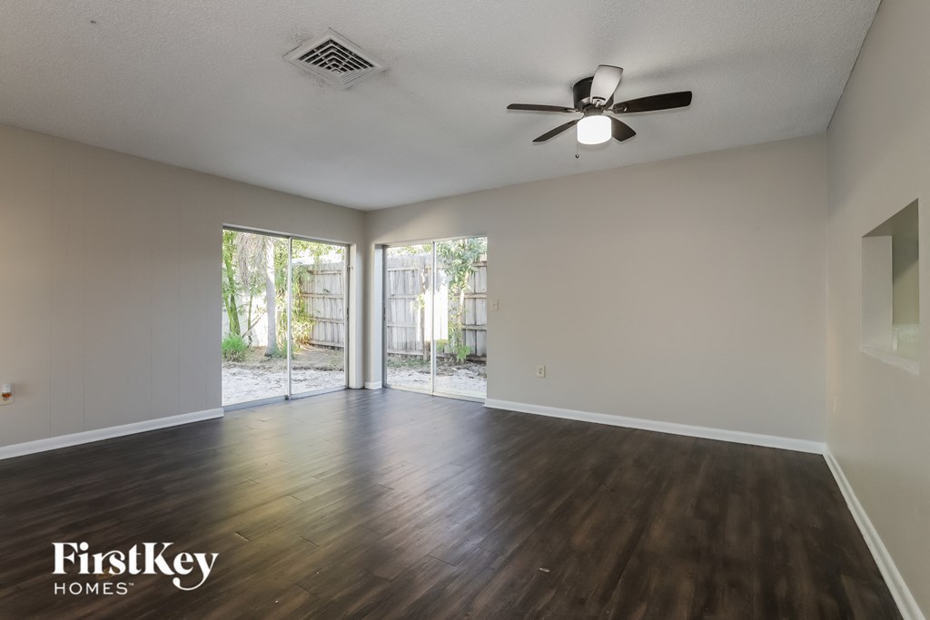 A spacious room with wooden floors and a ceiling fan.