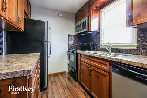 A kitchen with wooden cabinets and a black fridge.
