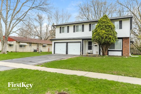 a white and brick house with a garage and a lawn