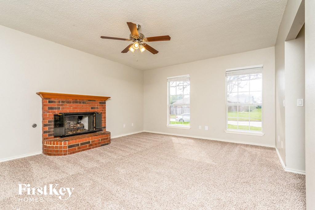a living room with a brick fireplace and a ceiling fan