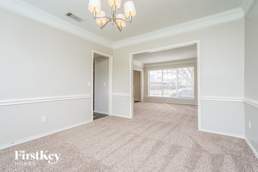 a empty living room with a chandelier and a window