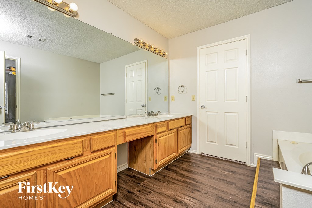 the master bathroom has a long vanity with two sinks and a large mirror