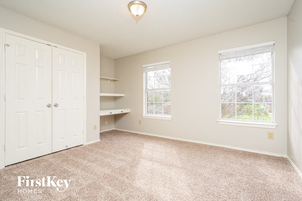 a bedroom with a closet and two windows