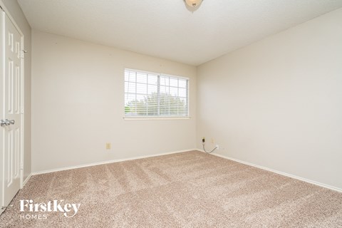 a spacious living room with carpet and a window