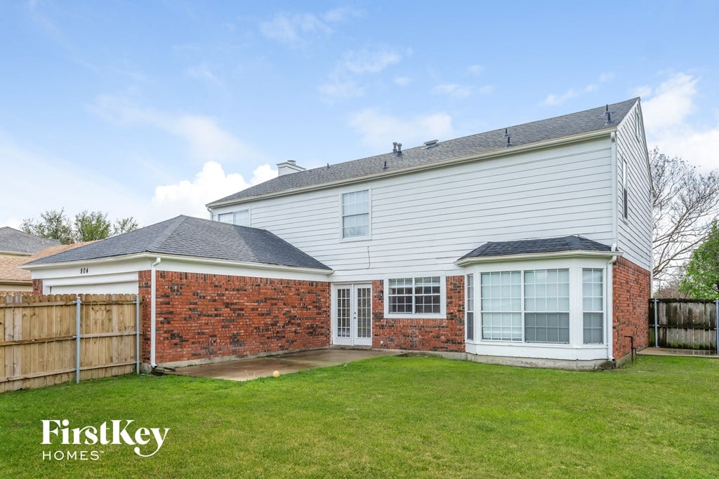 the backyard and exterior of a white house with a yard and a wooden fence