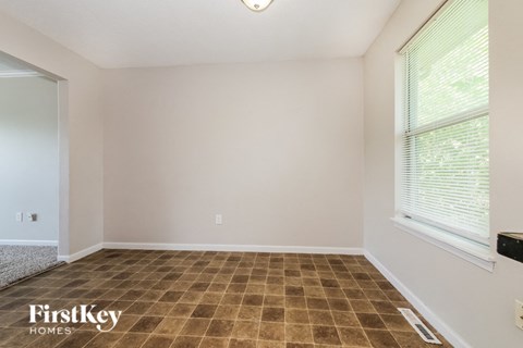 the living room of a home with a large window and tiled floors