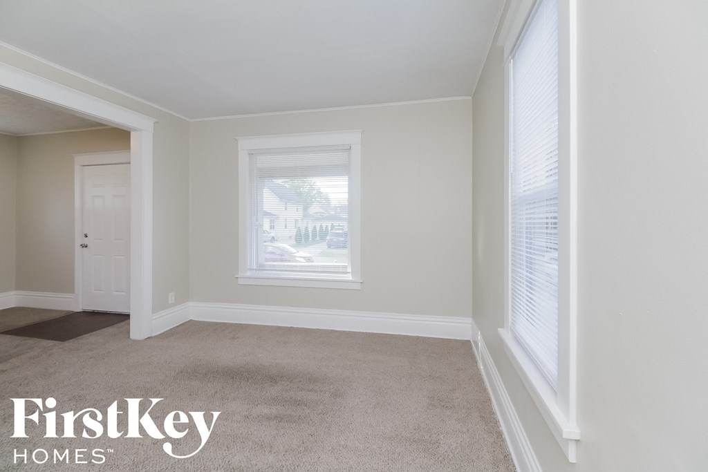 A room with a carpeted floor and a window with blinds.