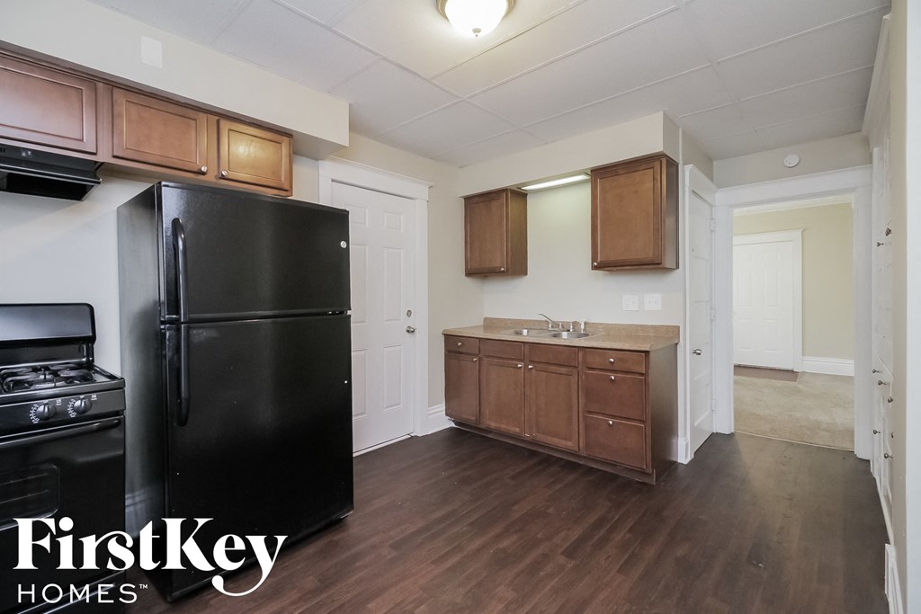 A kitchen with a black fridge and wooden cabinets.