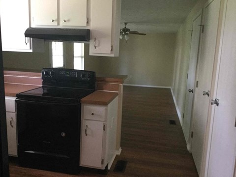 A black stove in a kitchen with white cabinets.