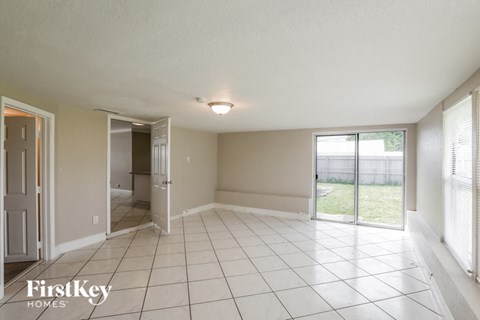 an empty living room with a sliding glass door to a yard