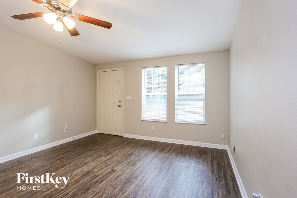 the living room of an empty house with wood floors and a ceiling fan