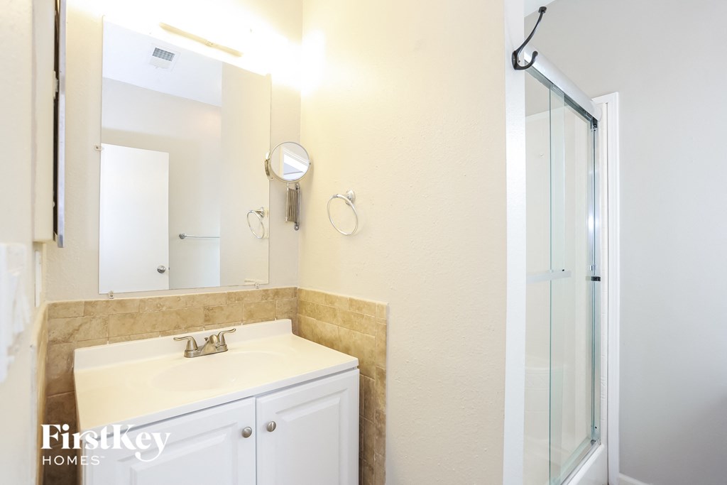 a bathroom with a sink and a shower and a mirror
