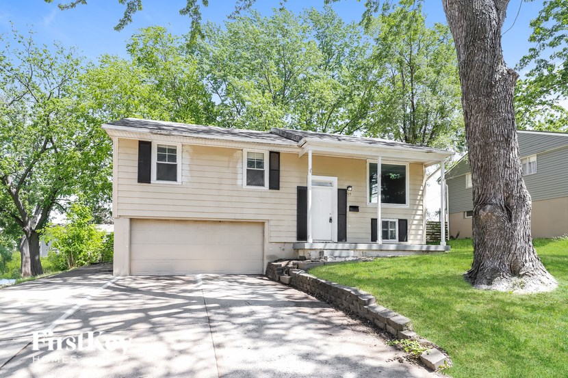 A house with a garage and a tree in front.