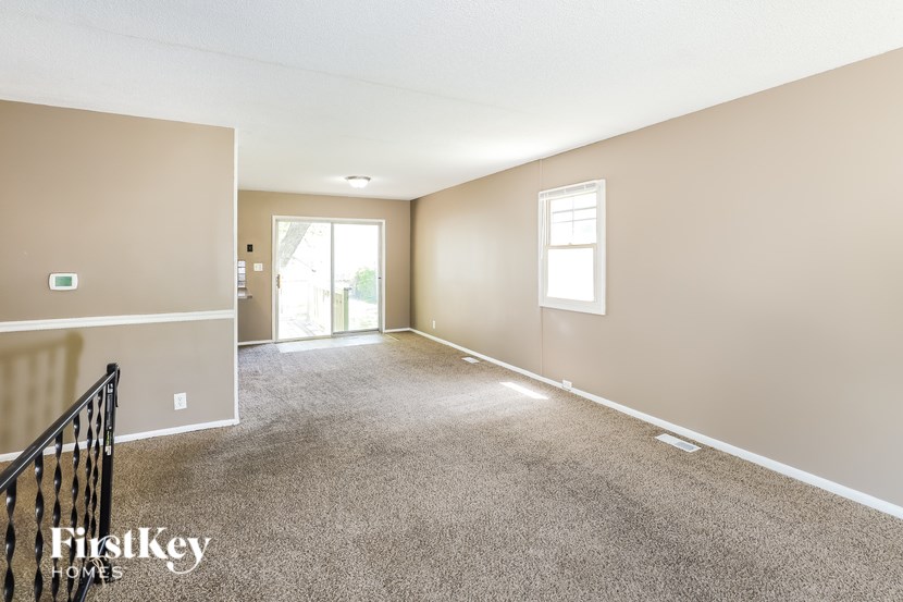 A spacious room with a carpeted floor and a window.
