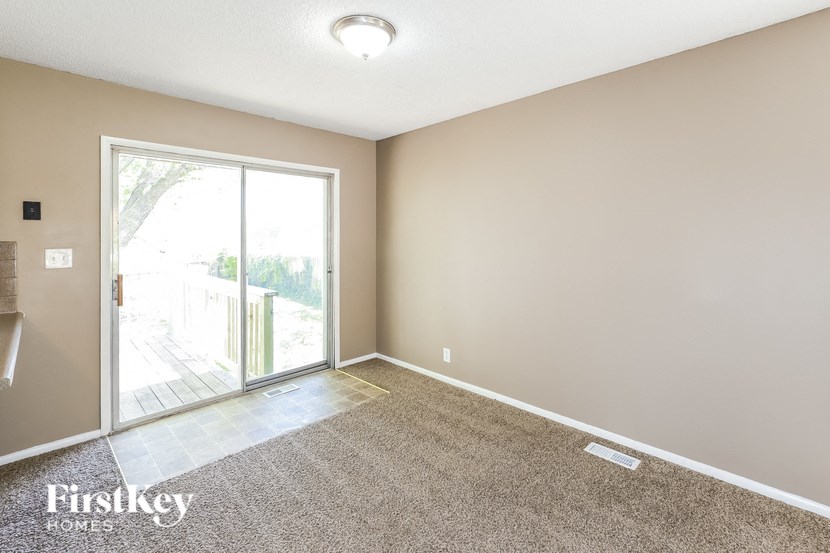 A room with a carpeted floor and a sliding glass door leading outside.