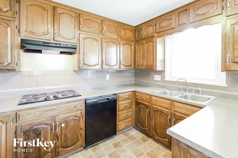 A kitchen with wooden cabinets and a black dishwasher.